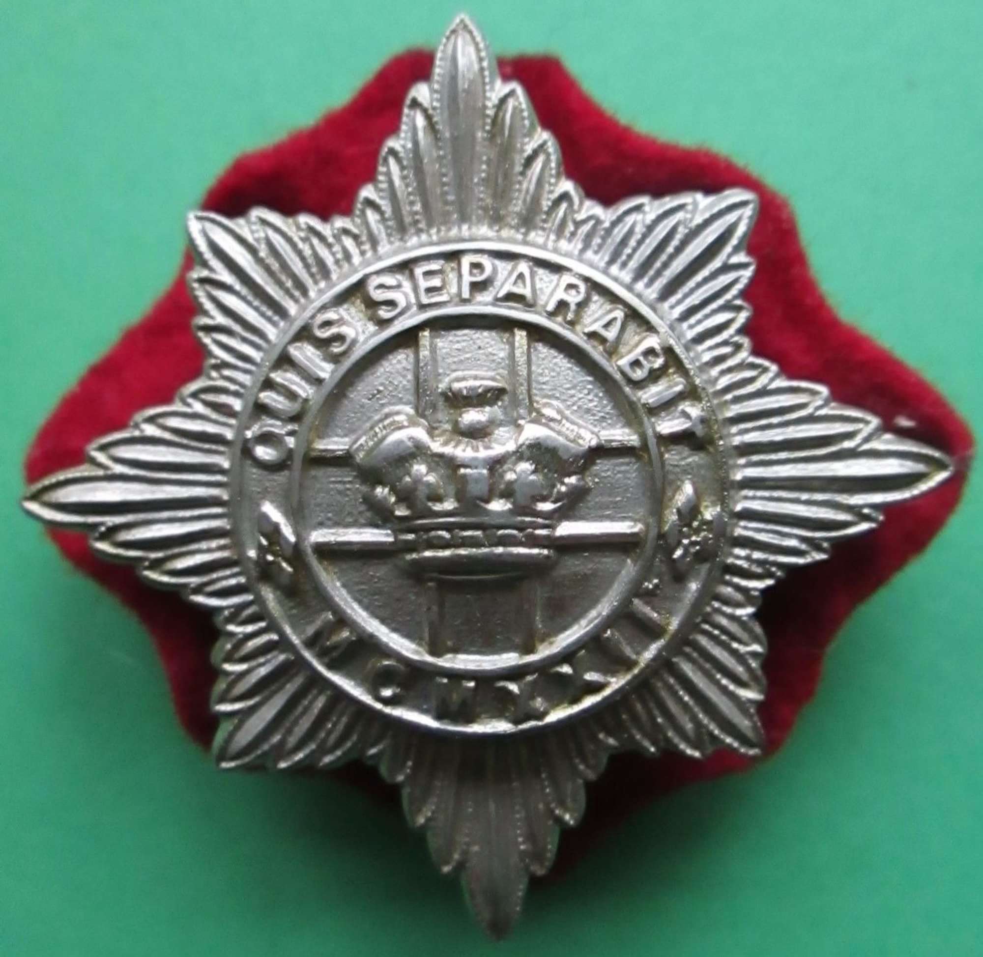 A 4TH / 7TH HUSSARS OTHER RANKS CAP BADGE WITH ITS RED BACKING CLOTH