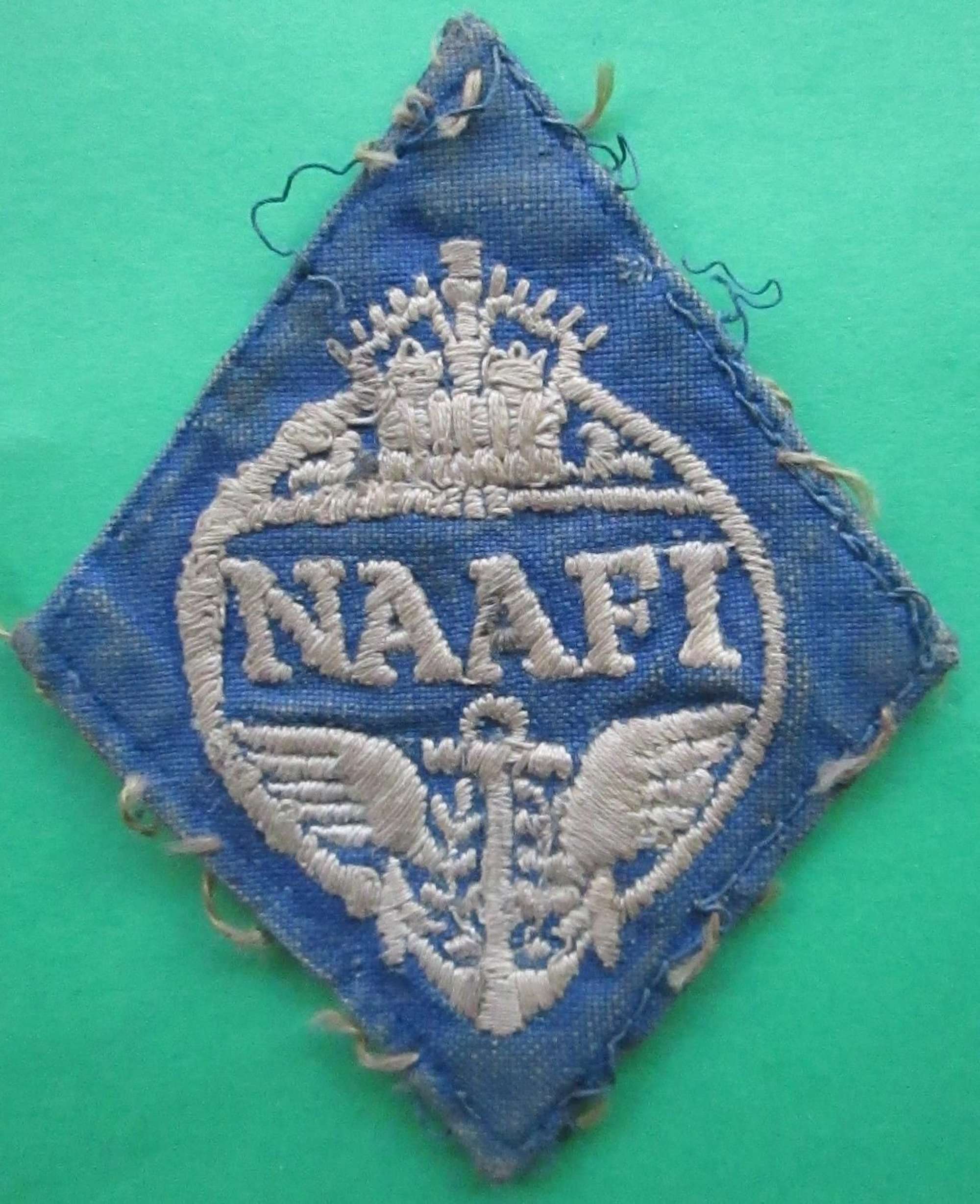 A WWII NAAFI WHITE AND BLUE BREAST OR CAP BADGE