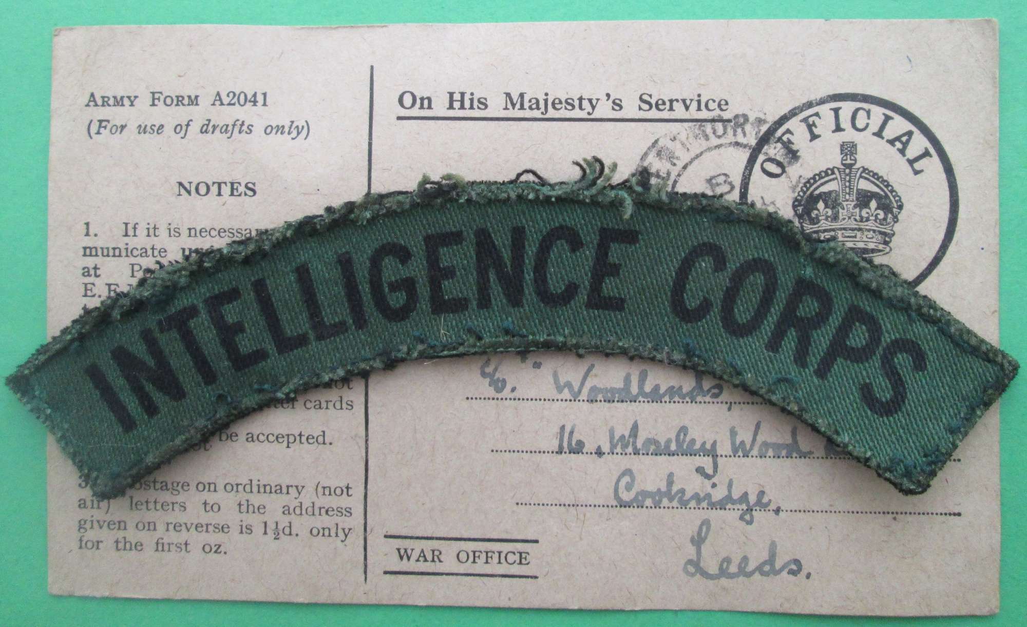 AN INTELLIGENCE CORPS SHOULDER TITLE WITH CORRESPONDING POSTCARD