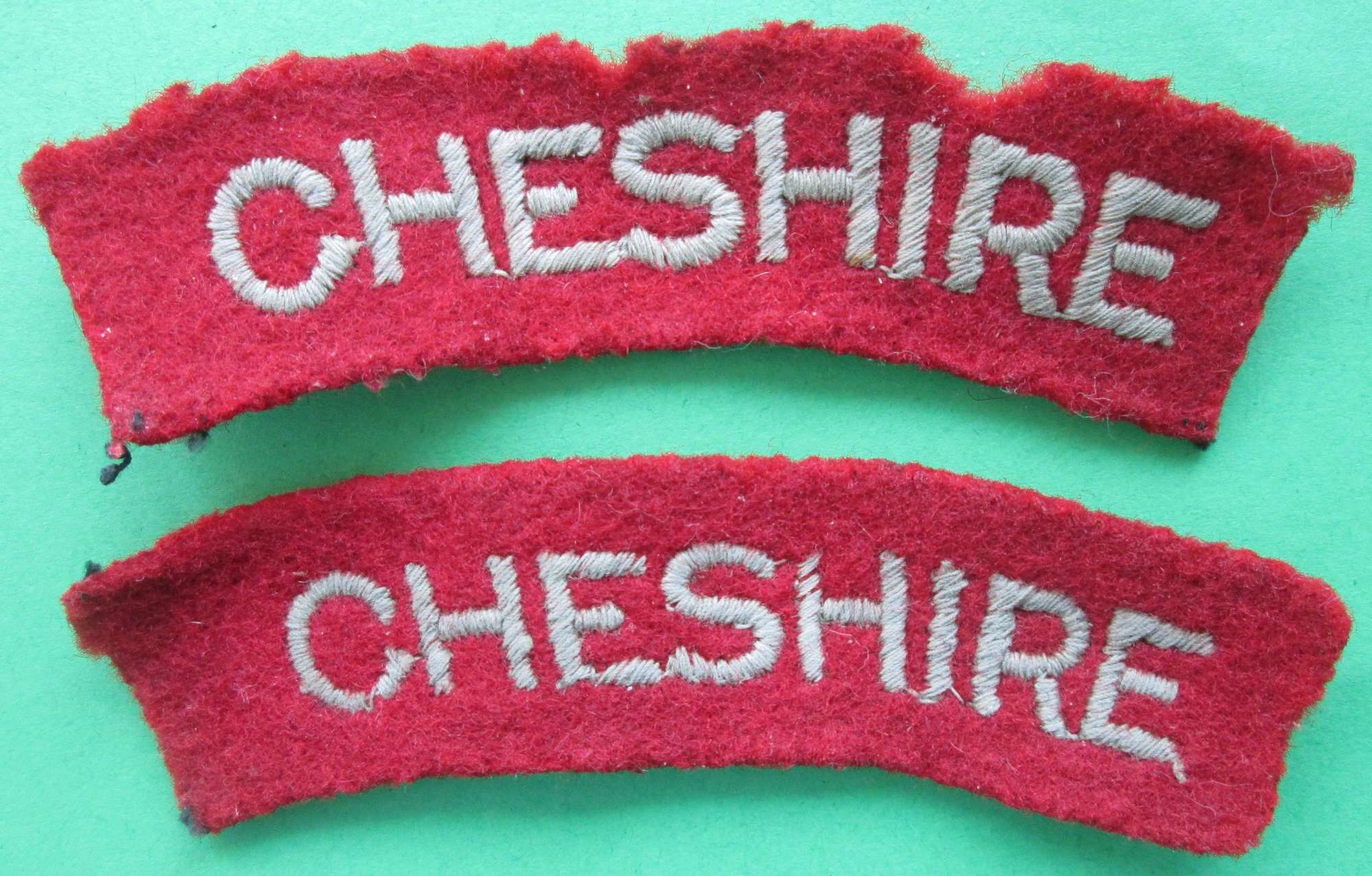 A PAIR OF CHESHIRE REGIMENT PASTE BACKED SHOULDER TITLES