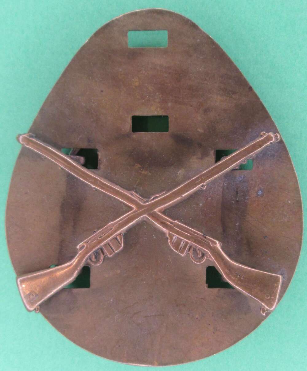 A Crossed rifles metal qualification badge with backing plate.